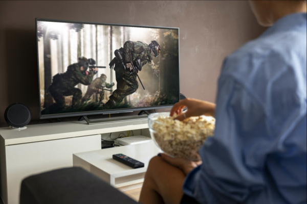 Watching an action movie on TV, showcasing the impact of dubbing content into Arabic for wider audience engagement.
